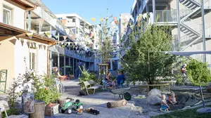 Der Innenhof der Arealentwicklung Teiggi in Kriens, eine grosszügige, verkehrsfreie Wohnstrasse mit Begrünung, Sitzgelegenheiten und Spielplatz.